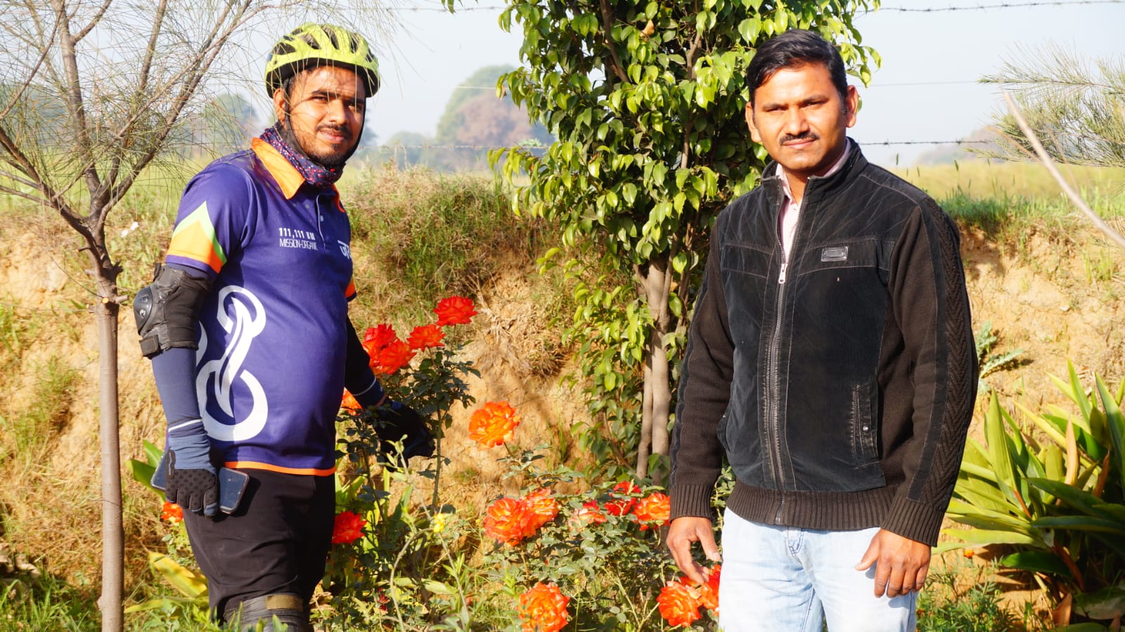 Two visitors standing near roses and plants